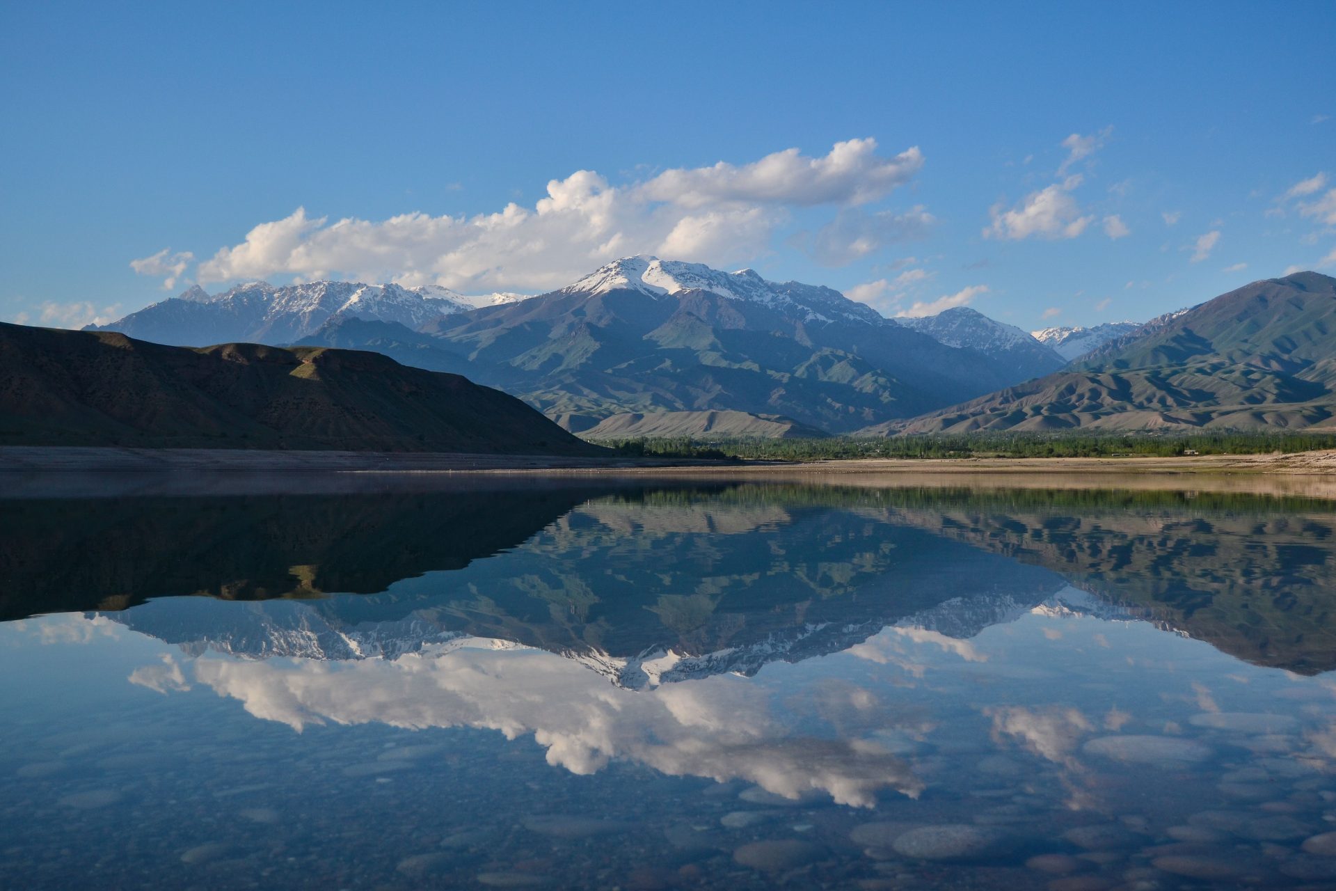Majestätische Berge, die sich in einem stillen See unter strahlend blauem Himmel spiegeln – ideal für Naturliebhaber.